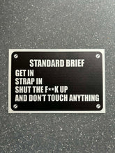 Load image into Gallery viewer, “Standard Brief: Get In, Strap In, Shut The F**k Up” Military Humour Car plaque